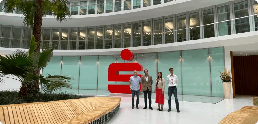 CEO von docu tools, Projektleiter und Team der Hamburger Sparkasse vor dem Sparkassen-Logo im Atrium des Deutschlandhauses