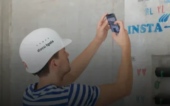 Mitarbeiter mit docu tools Helm dokumentiert technische Installation mit Smartphone auf der Baustelle