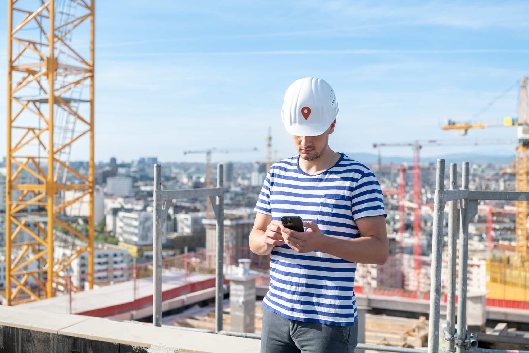 Bauleiter nutzt ein Smartphone auf der Baustelle zur mobilen Erfassung und Prüfung digitaler Baudaten.